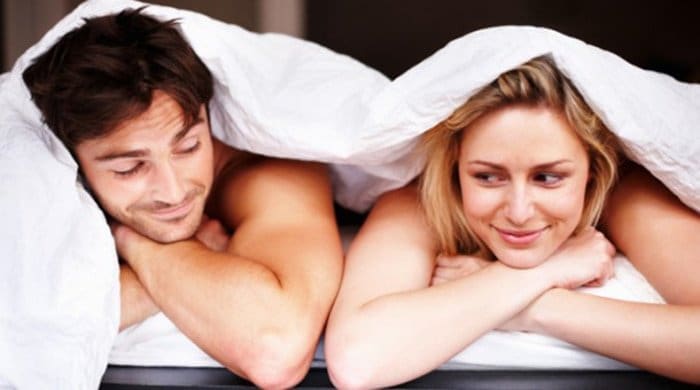 A guy in bed with a woman after having sex