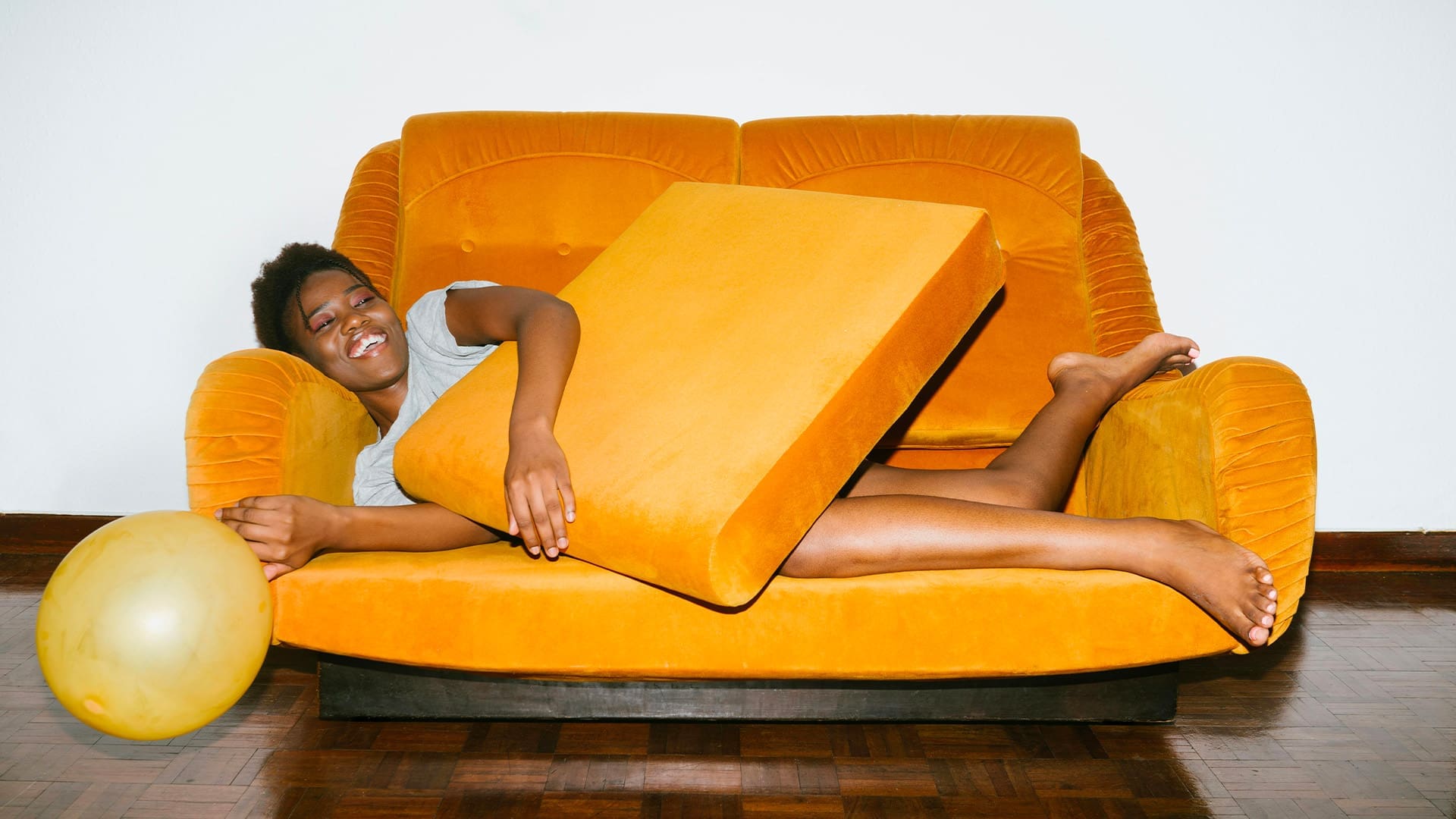 Woman lying on yellow couch with a balloon