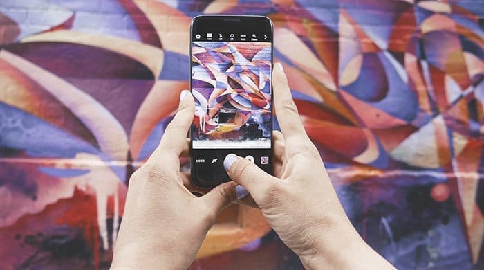A woman taking a picture of graffiti with her phone