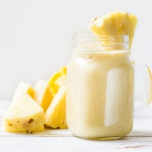Mango, Banana, Pineapple and Oatmeal Smoothie in the Jar with Ingredients nearby on the Pastel Pink Background