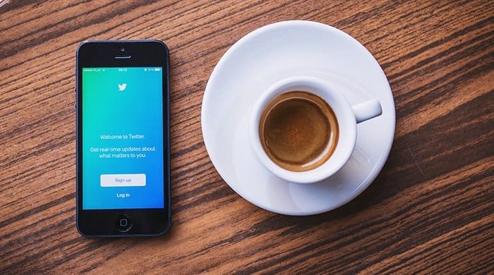 phone with twitter on a table next to a cup of coffee for anxiety