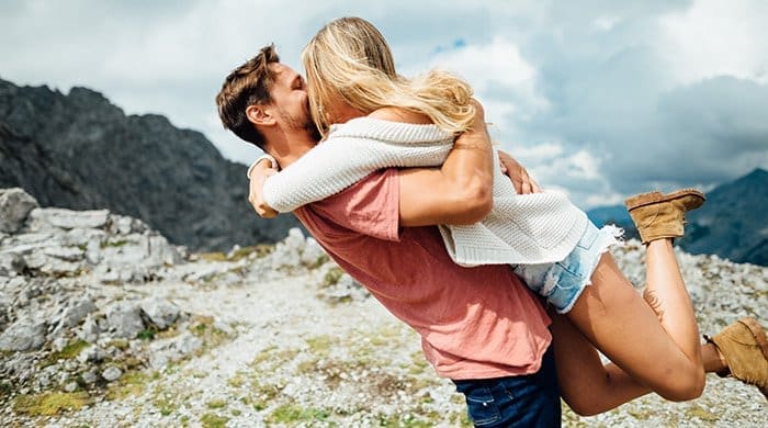 A couple hugging on top of a cliff to symbolise first love