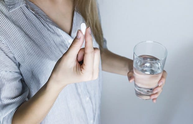 A woman holding the abortion pill and a glass of water