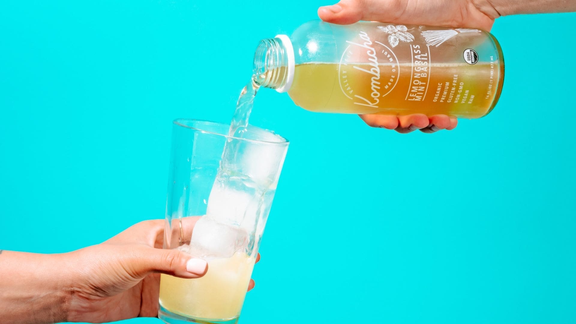 Kombucha poured into a glass with a blue background