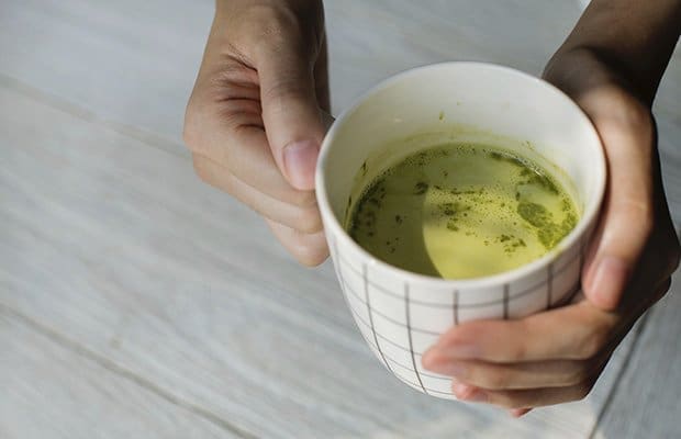 A closeup of a women's hands holding a cup of tea made from one of the popular detox teas on the market