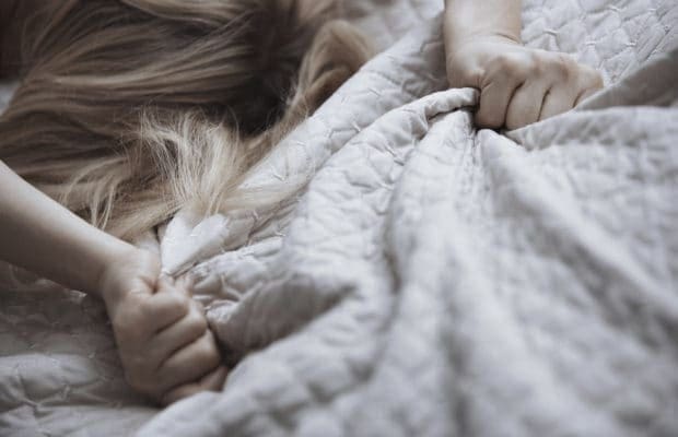 A close-up of a woman lying on a bed trying out oral sex positions