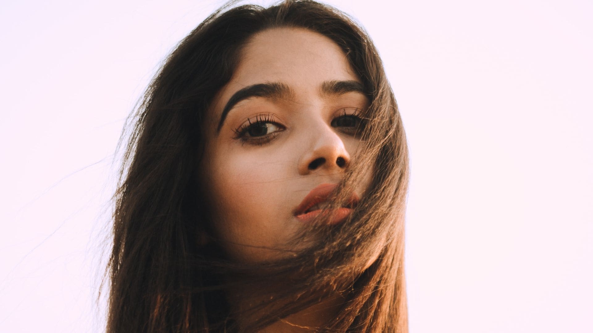 woman using sun protection for hair products with pink sky