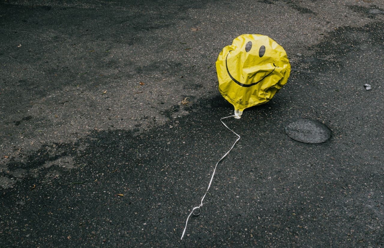 smiling balloon crumpled on the street