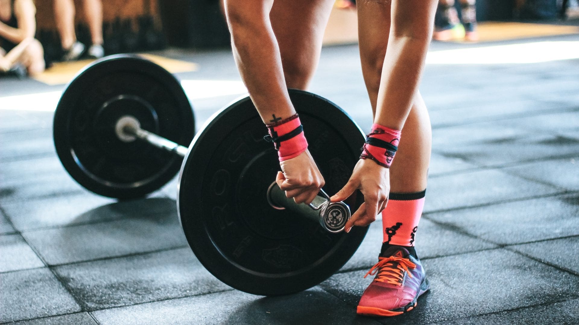woman who wants to know how to start weightlifting putting weights on a barbell