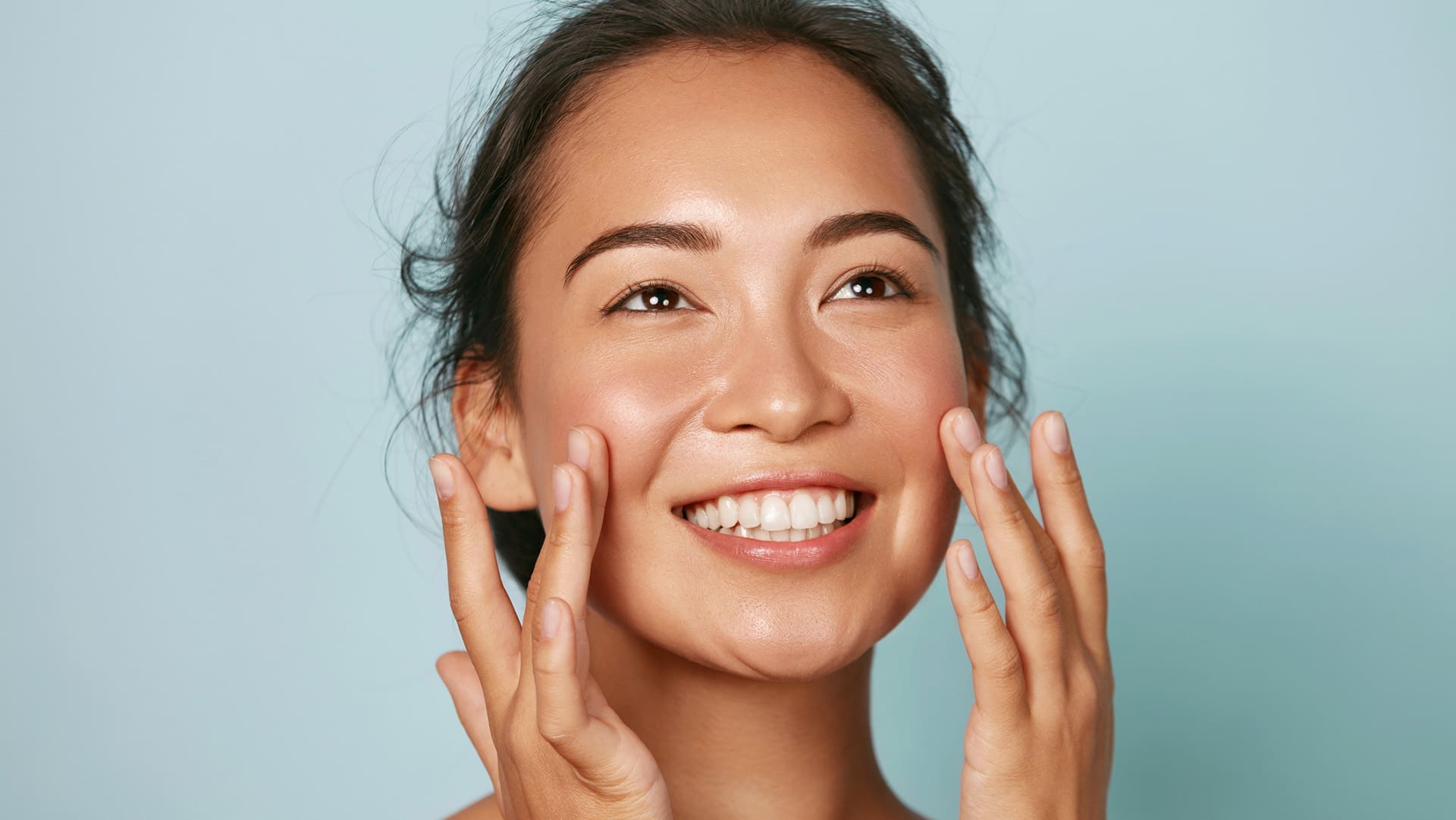 Woman applying moisturiser onto her face.