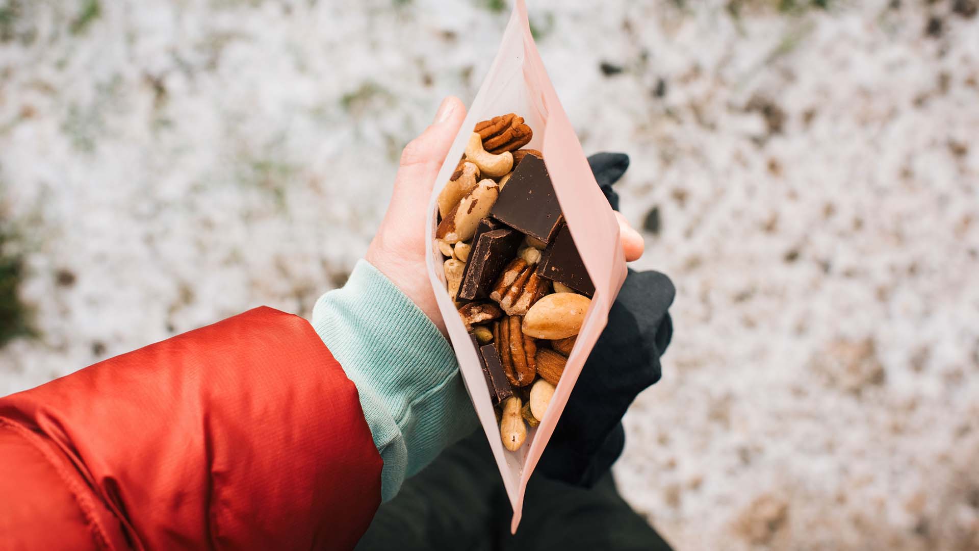 woman holding trail mix in a reusable snack bag whilst hiking